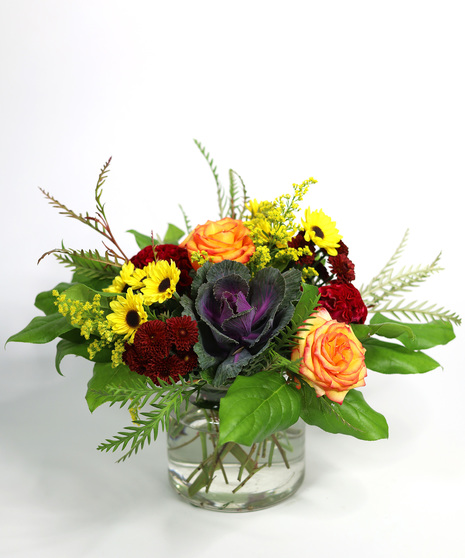 kale, roses and sunflowers in a glass vase