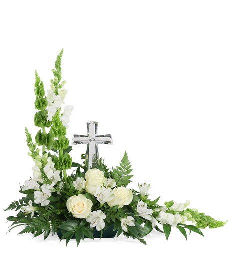 White and green sympathy arrangement with silver cross, white roses, snapdragons, alstroemeria, and fern greenery.