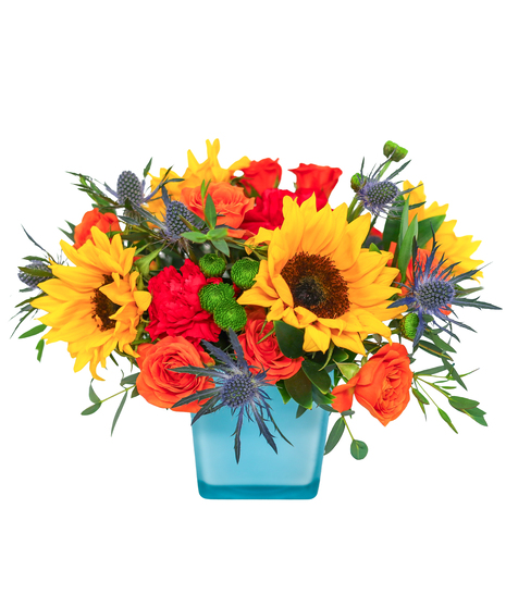 Vibrant arrangement of yellow sunflowers, orange roses, hot pink carnations and blue thistles in a turquoise vase.